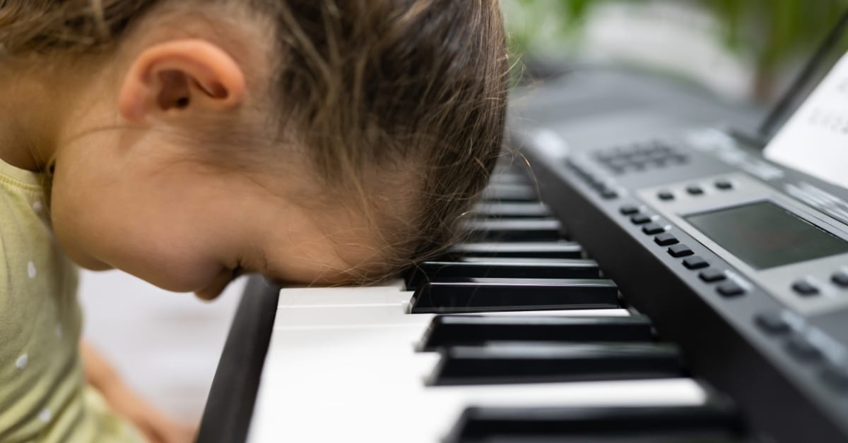 Frustrated child with head resting at a piano.