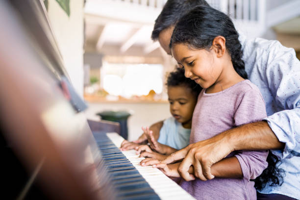 Father playing piano with two children